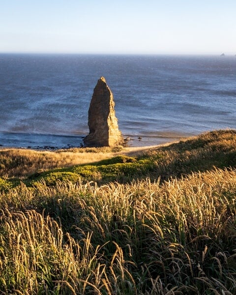 Prominent sea stack adjacent to lighthouse.